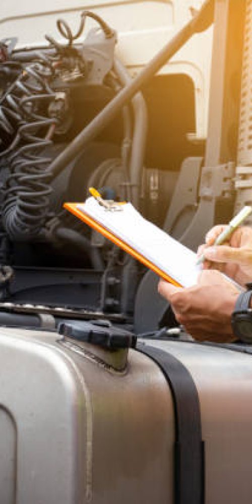 Truck inspection and safety. Truck driver writing on clipboard with checking truck fuel tank.